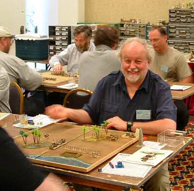 Don Ray of Calgary, Alberta smiles for the camera while playing 15mm Sumerians in the 'Hot Wheels' DBA Ancients tourney.  Two of the four DBA tables can be seen, along with the space along the wall for us neatly to store all our DBA armies thru convention.   We we dubbed it 'DBA Street'